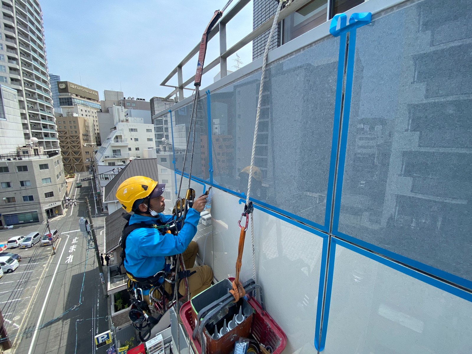 広島の高層建物でロープアクセスによる雨漏り調査を行う作業員